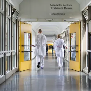 Arzt und Ärztin von hinten in Krankenhausflur zu sehen