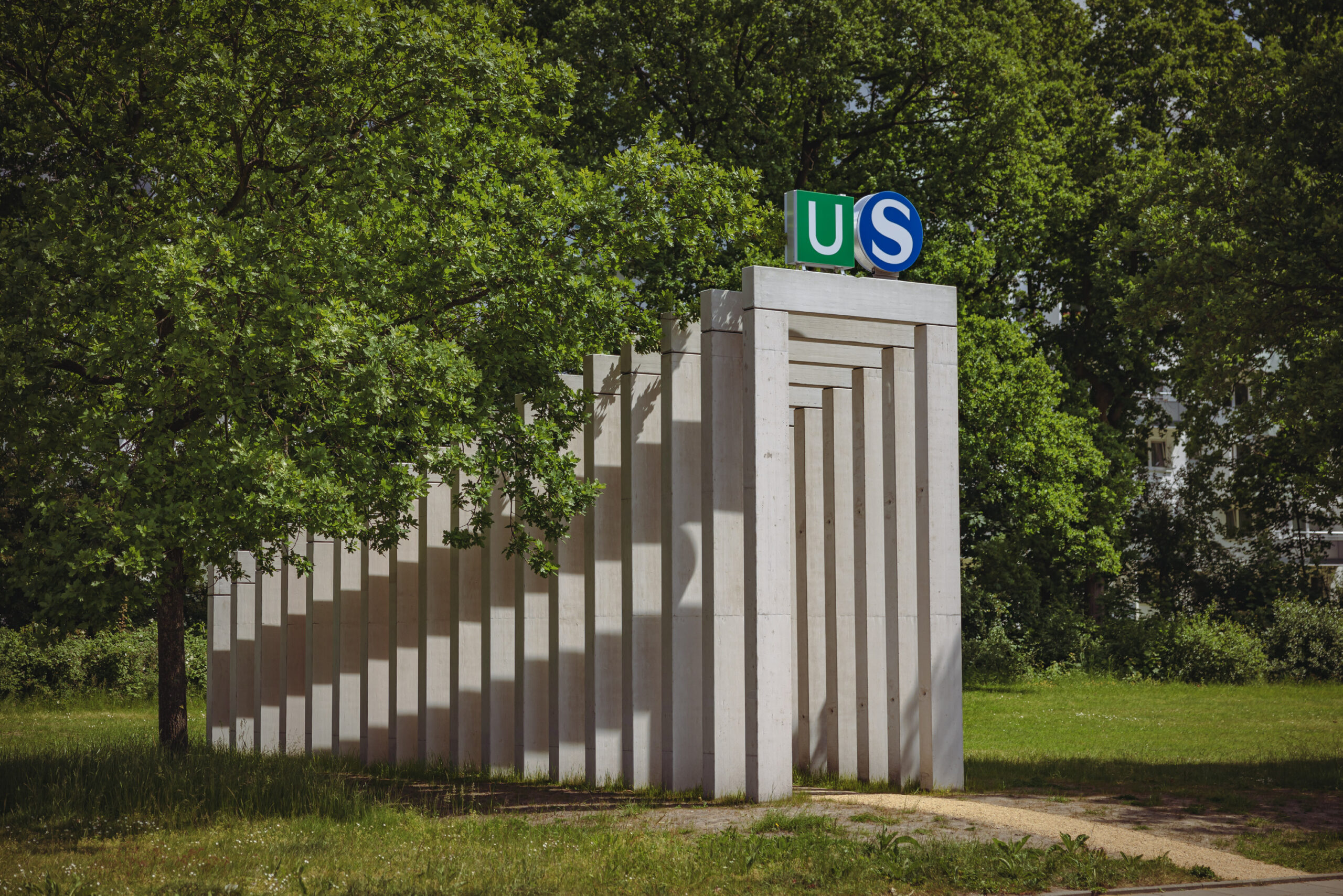 Osdorf: mehrere Betonsäulen bilden einen Bogengang, am Eingang die Logos für U- und S-Bahn