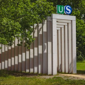 Osdorf: mehrere Betonsäulen bilden einen Bogengang, am Eingang die Logos für U- und S-Bahn