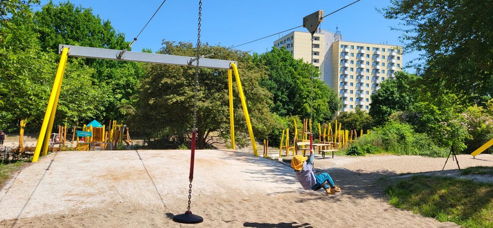 Kind auf einer Seilbahn mit Spielplatz im Hin tergrund