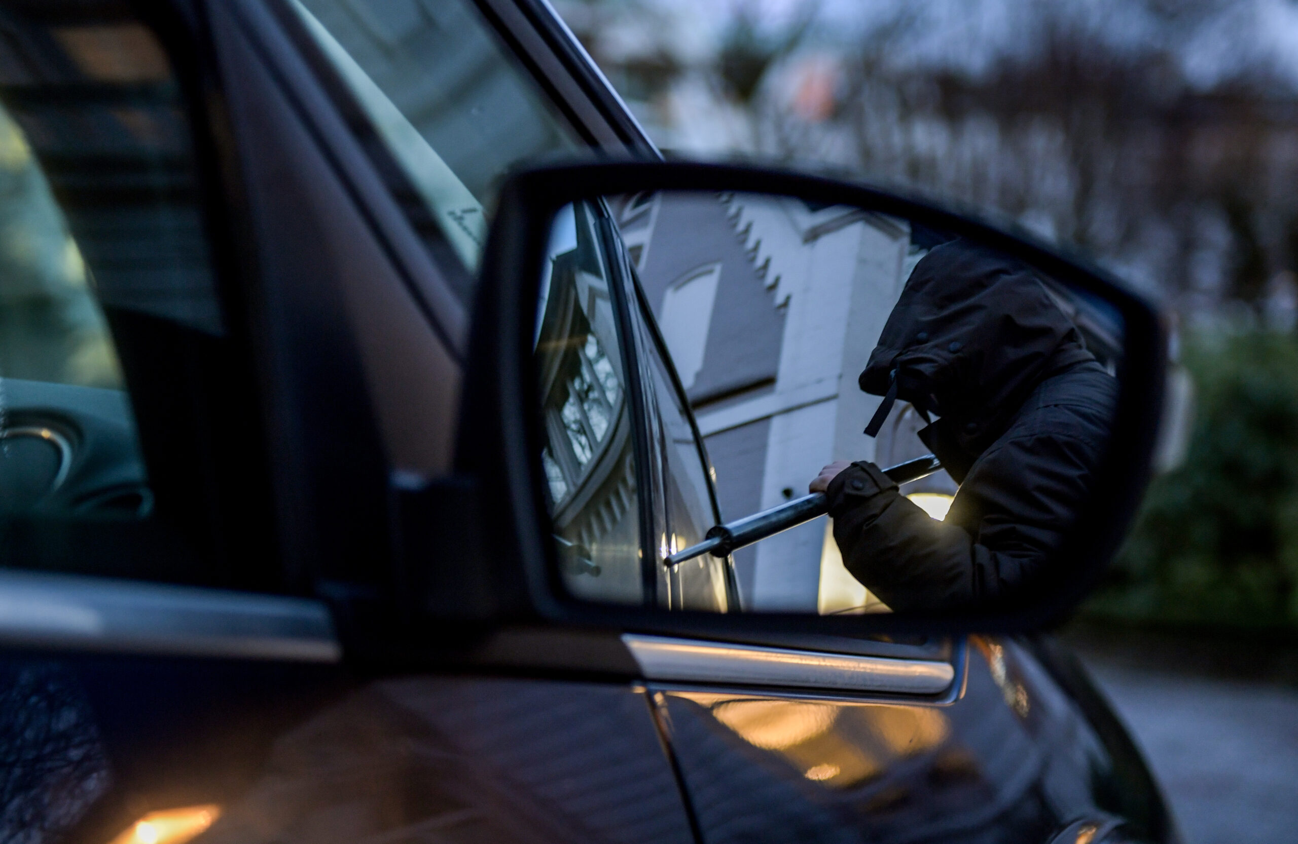 Symbolfoto: Ein Mann versucht eine Autotür mit einer Metallstange aufzubrechen