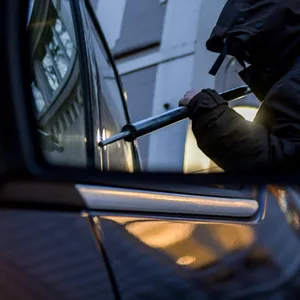 Symbolfoto: Ein Mann versucht eine Autotür mit einer Metallstange aufzubrechen