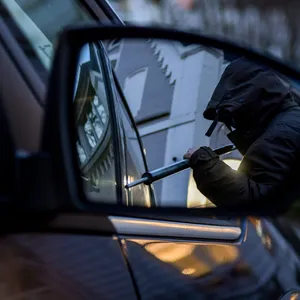 Symbolfoto: Ein Mann versucht eine Autotür mit einer Metallstange aufzubrechen
