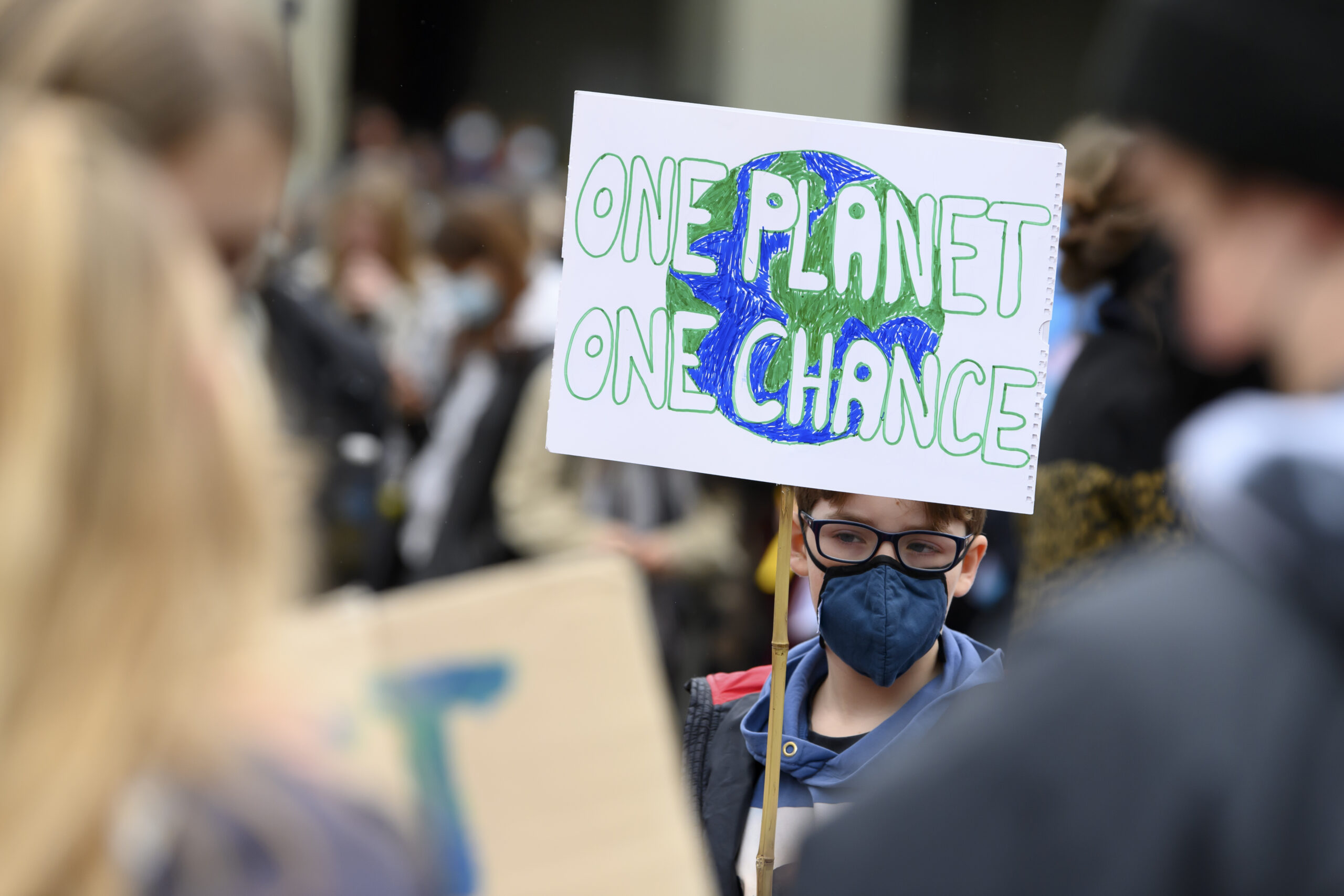Ein Junge hält ein Plakat hoch, auf dem steht "One planet, one Chance“