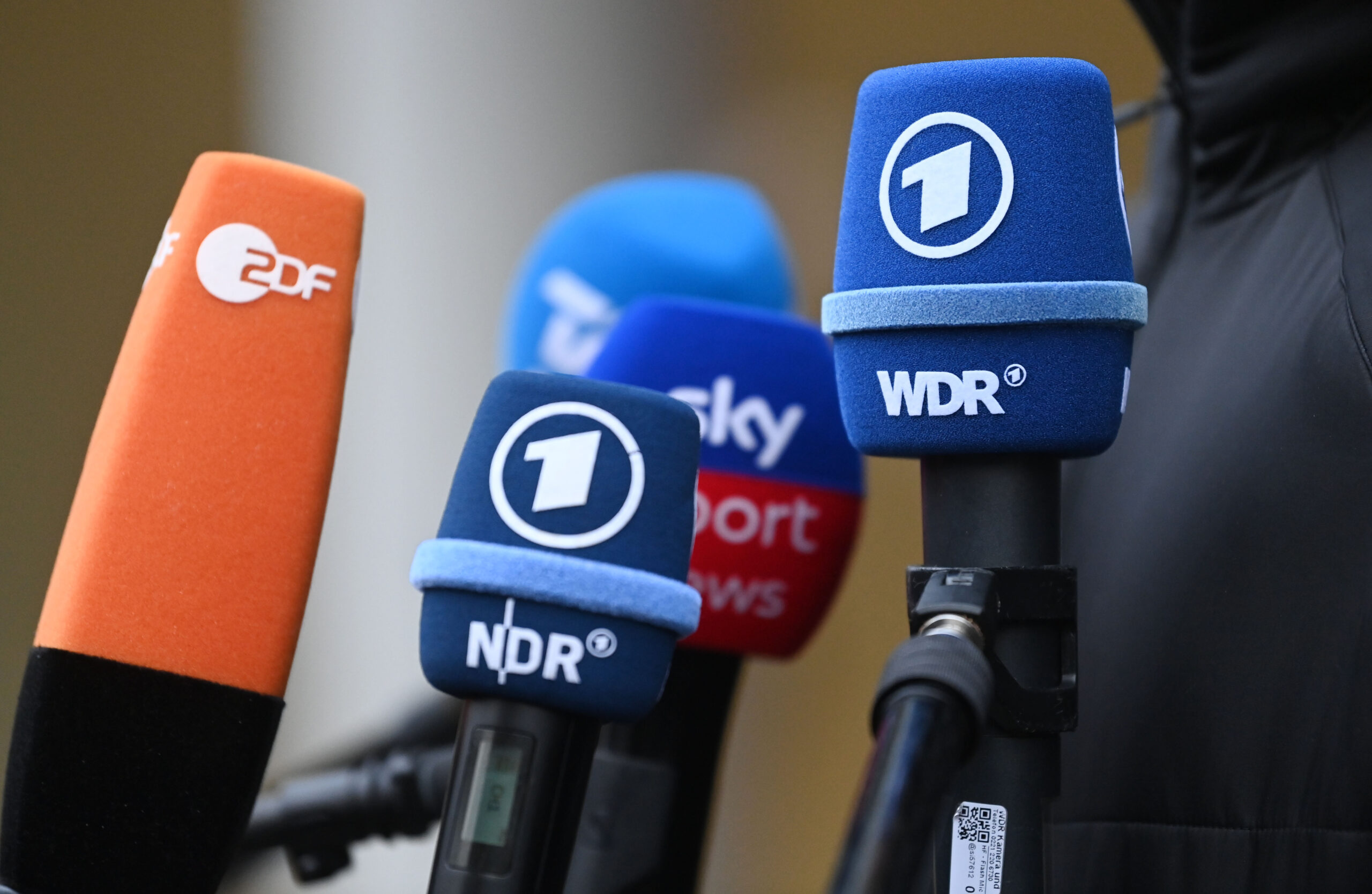 Mikrofone mit Logos von ZDF, ARD und Sky sind während einem Medientermin vor dem Mannschaftshotel der deutschen Handball-Nationalmannschaft zu sehen.