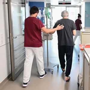 Ein Pfleger mit einem Patienten im Krankenhaus. (Symbolbild)