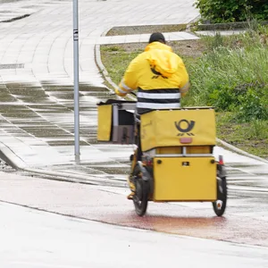 Briefträger fahren auf ihren Dienstfahrrädern ihre Tour.