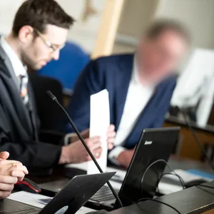 Der Angeklagte (r) sitzt vor Prozessbeginn mit seinen Anwälten Viktor Volkmann (l) und Sebastian Vogel im Gerichtssaal.