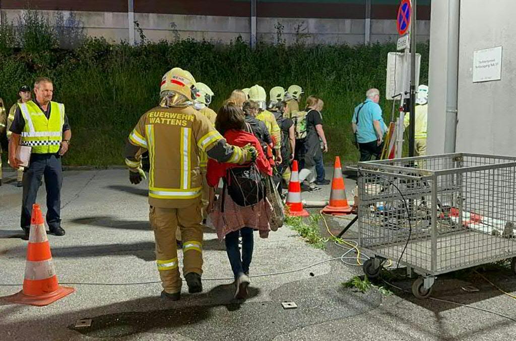 Rettungskräfte kümmern sich bei Innsbruck um Zugreisende nach einem Brand in einem Bahntunnel.