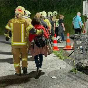 Rettungskräfte kümmern sich bei Innsbruck um Zugreisende nach einem Brand in einem Bahntunnel.
