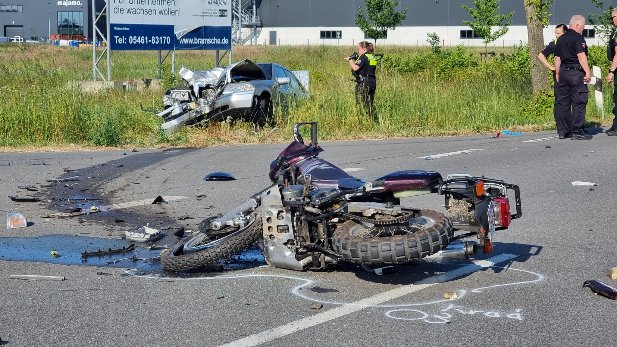 Ein Motorrad liegt nach einem Unfall auf der Straße, im Hintergrund das beteiligte Auto