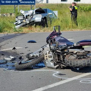 Ein Motorrad liegt nach einem Unfall auf der Straße, im Hintergrund das beteiligte Auto