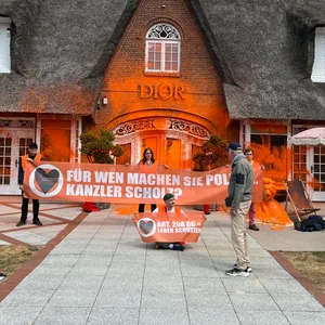 Klima-Aktivisten haben sich vor einem besprühten Luxusgeschäft auf der Insel Sylt platziert.