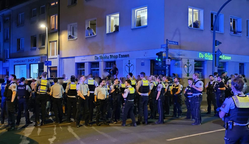 Polizisten bewachen Mitglieder einer anderen der beteiligten Gruppen einer Schlägerei in der Innenstadt.