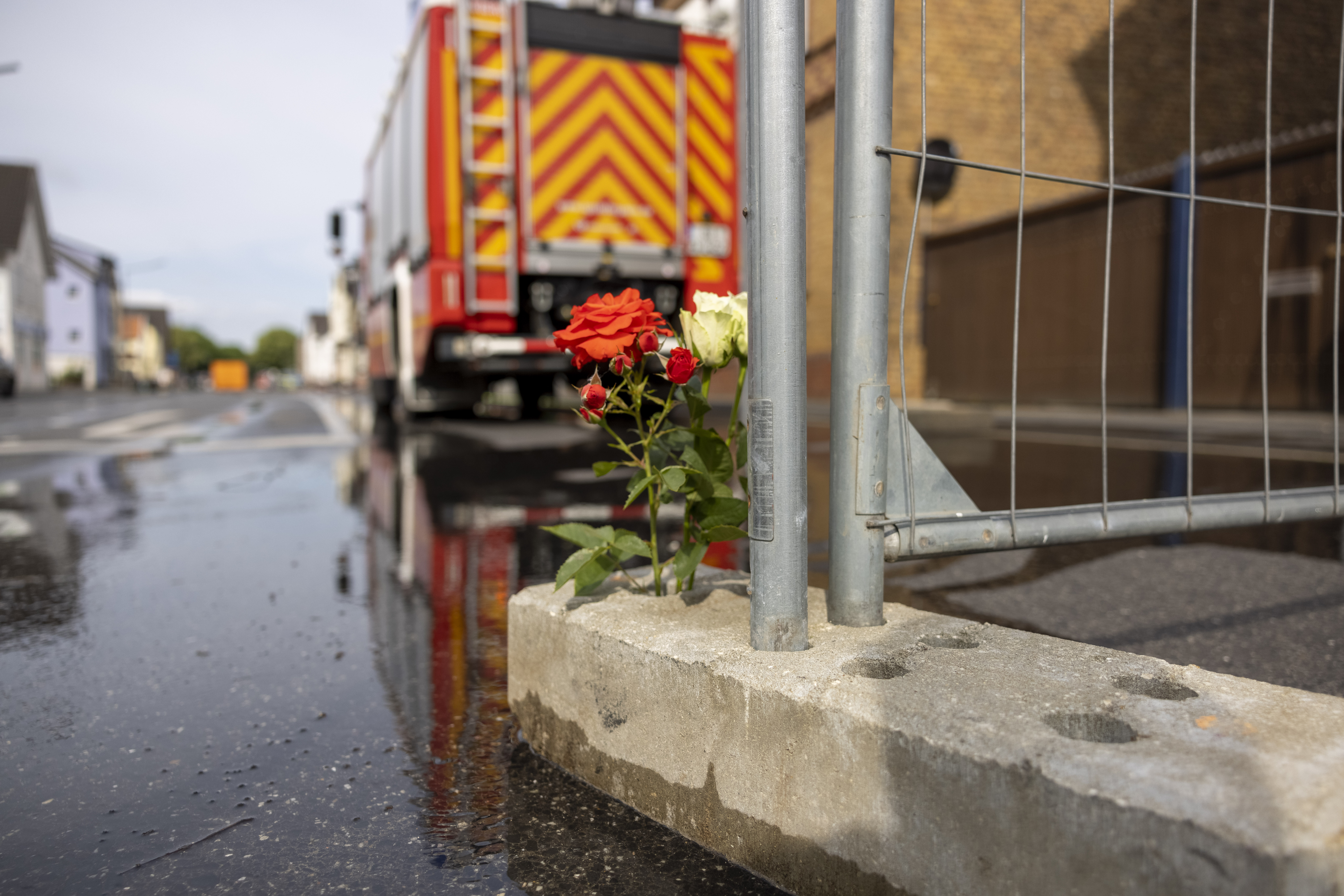 Blumen stehen am Absperrgitter in der Nähe der Brandstelle, wo am vergangenen Sonntag zwei Feuerwehrleute tödlich verunglückten.