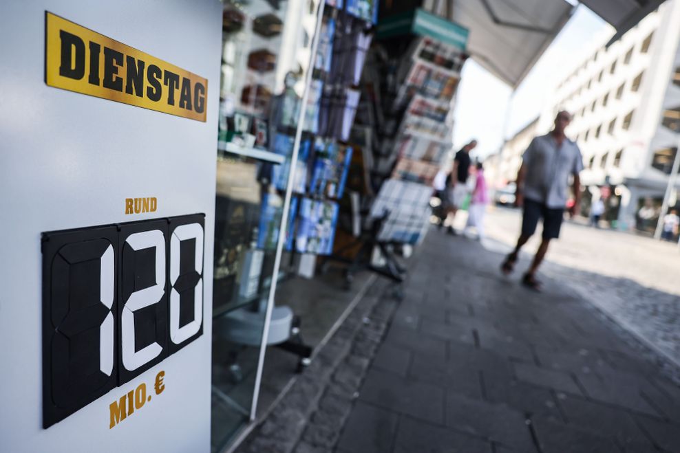 Ein Schild mit der Aufschrift „Dienstag – Rund 120 Mio. Euro“ steht vor einem Tabak- und Zeitschriften-Geschäft.