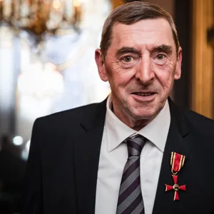 Daniel Nivel lächelt in die Kamera im Anzug mit dem Bundesverdienstkreuz.