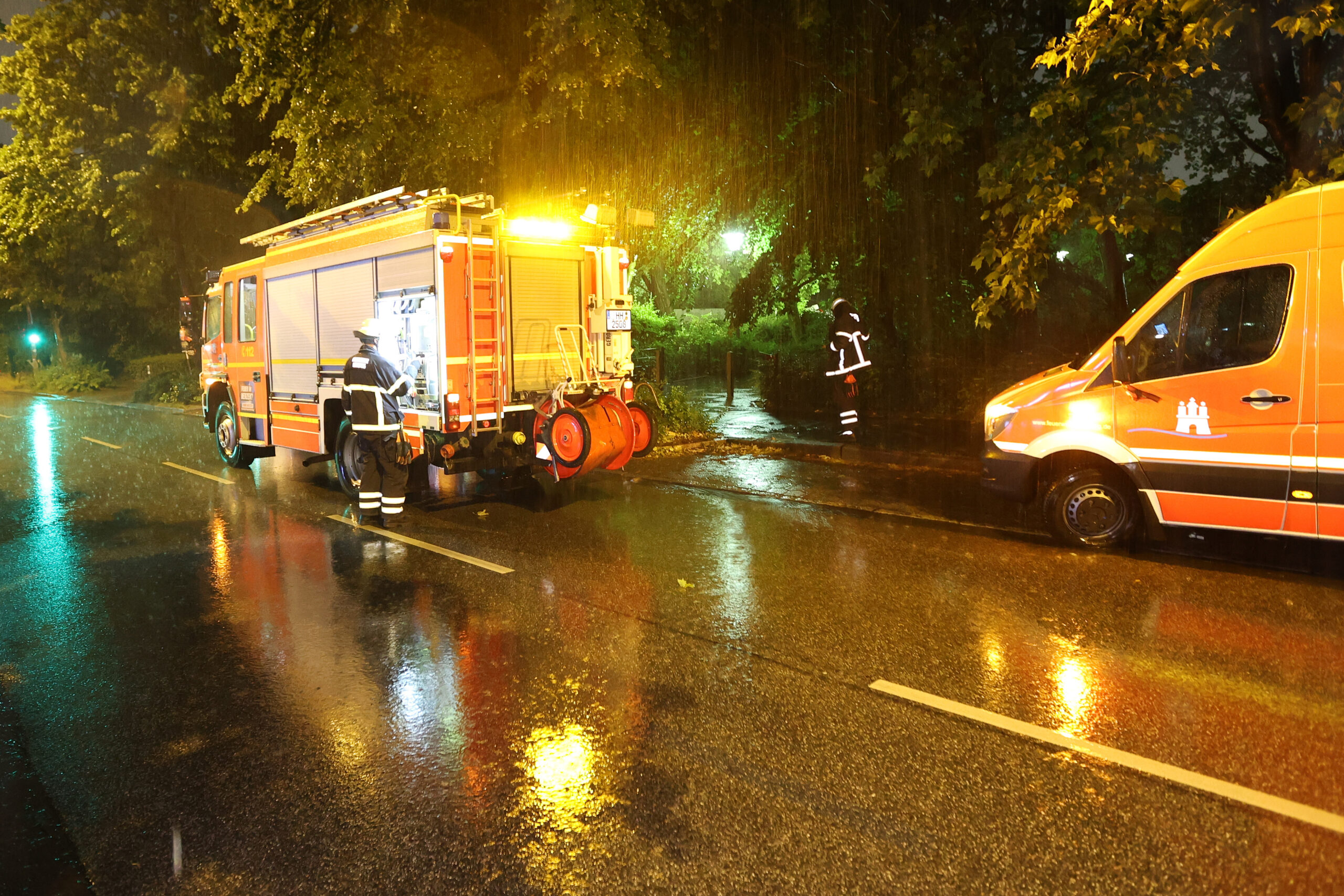 Einsatzkräfte der Feuerwehr pumpen in der Nacht Regenwasser aus einem Keller auf die Straße.