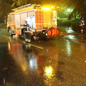 Einsatzkräfte der Feuerwehr pumpen in der Nacht Regenwasser aus einem Keller auf die Straße.
