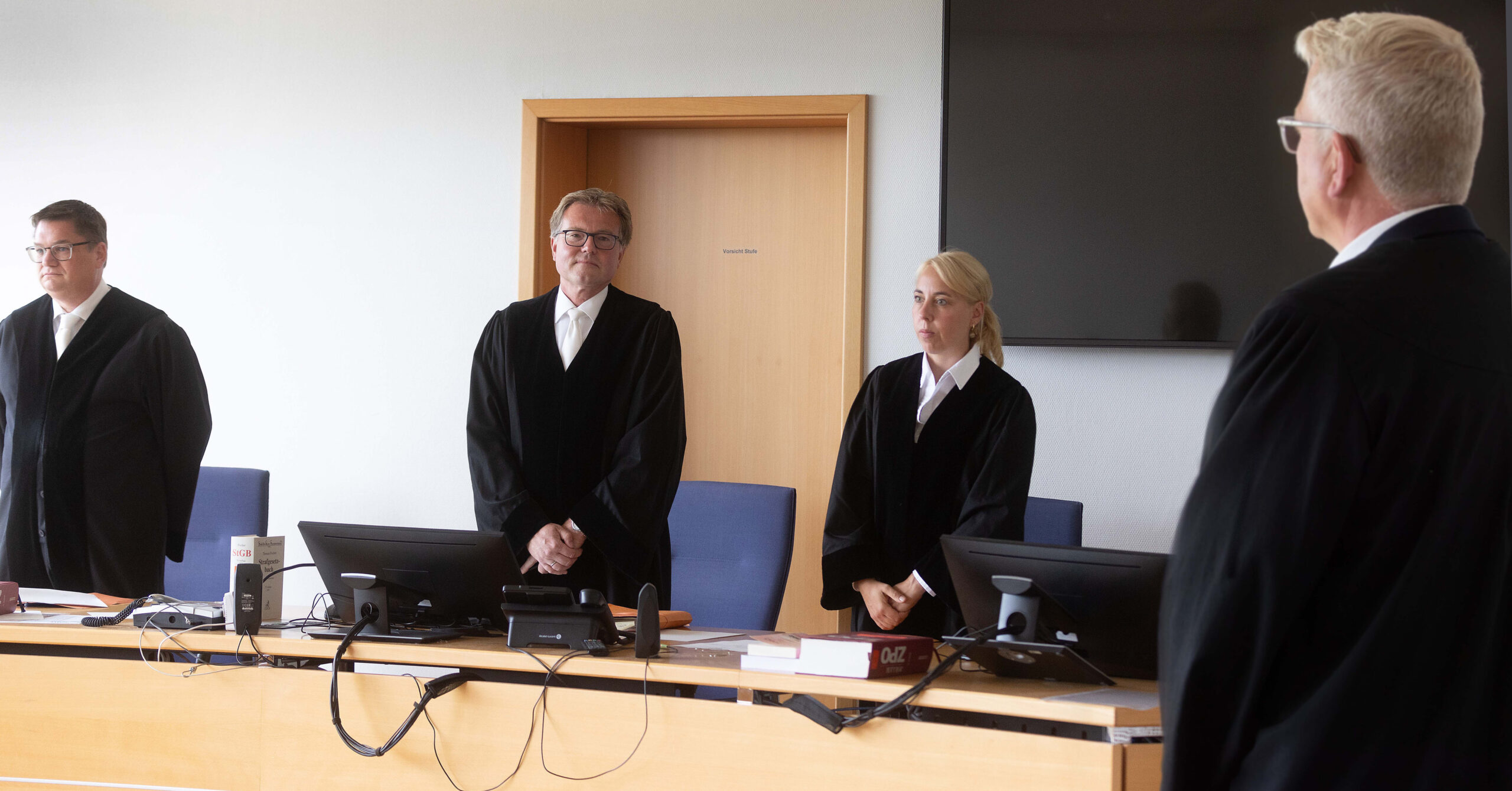 Martin Saal (2.v.l), Vorsitzender Richter, und Richard Uhle (r), Rechtsanwalt, stehen im Verhandlungssaal des Oberlandesgerichts Hamm.