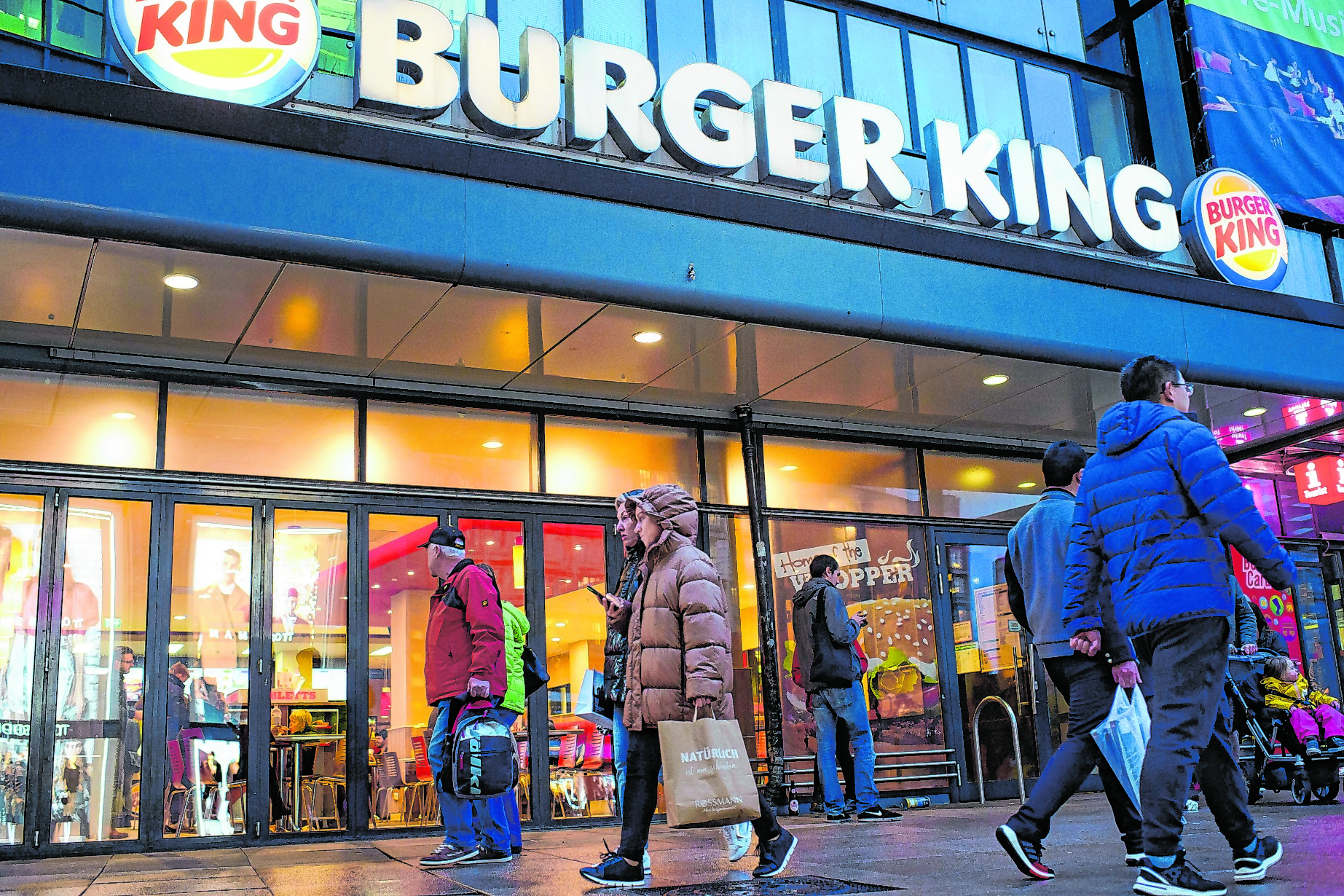 Passanten gehen am Abend an einer Burger King-Filiale auf dem Alexanderplatz in Berlin vorbei.