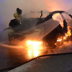 Feuerwehrkräfte löschen die Flammen. Das Auto wurde komplett zerstört.