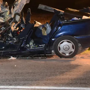 Der völlig zerstörte Mercedes, im Hintergrund der Rettungshubschrauber, mit dem der Fahrer ausgeflogen wurde