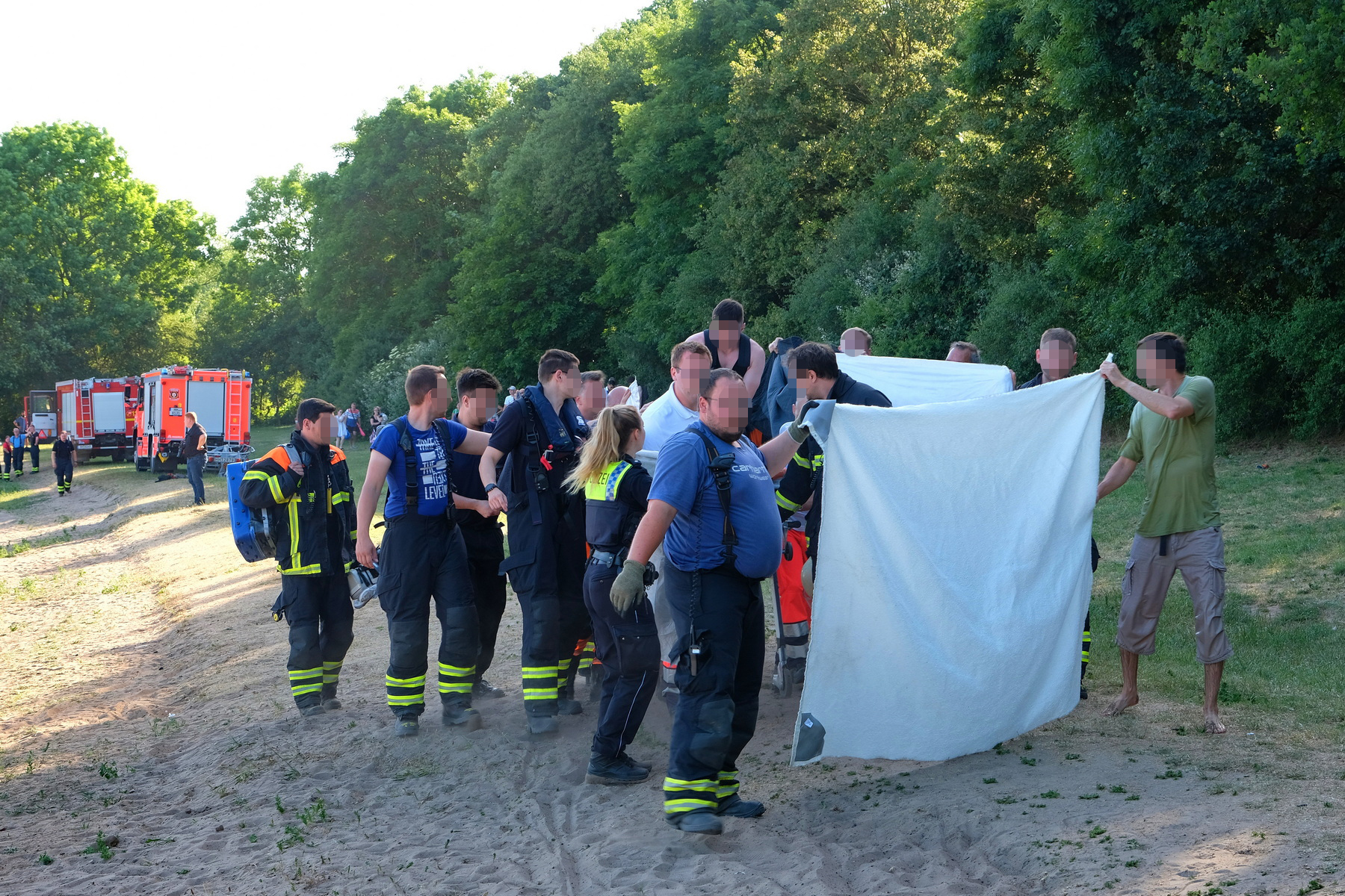 Rettungskräfte von Polizei und Feuerwehr sowie freiwillige Helfer sind am Seeufer im Einsatz.