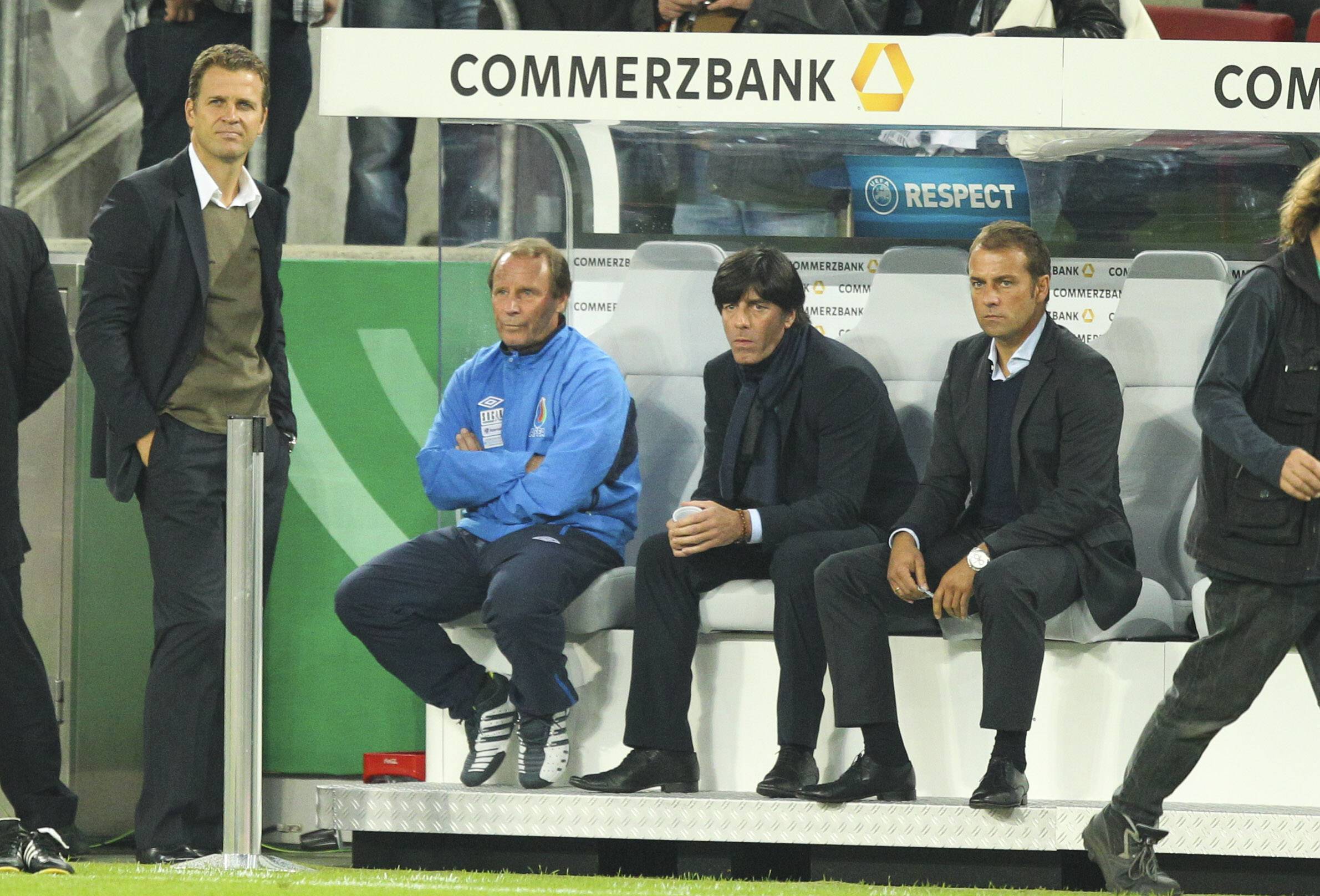 Berti Vogts als Nationaltrainer von Aserbaidschan sitzt auf der Bank neben Jogi Löw und Hansi Flick.