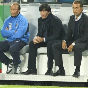Berti Vogts als Nationaltrainer von Aserbaidschan sitzt auf der Bank neben Jogi Löw und Hansi Flick.