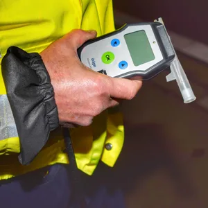 Ein Polizist hält ein Alkoholtestgerät in der Hand. (Symbolbild)