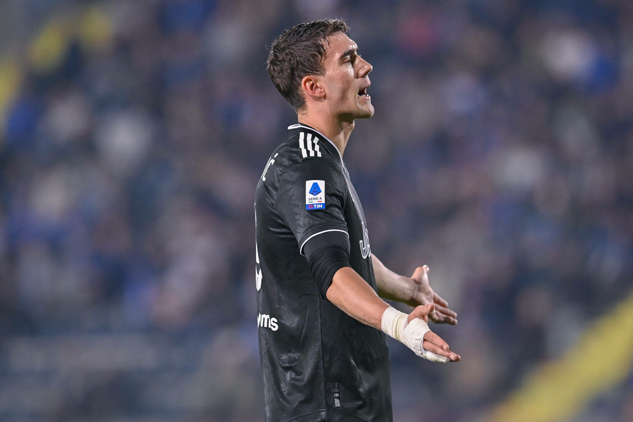 Dusan Vlahovic im schwarzen Trikot von Juventus Turin gestikuliert und breitet die Arme aus.