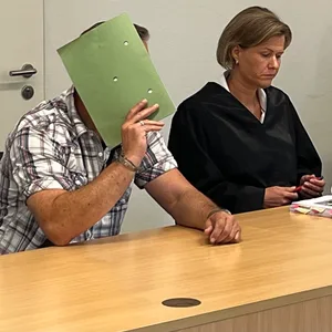 Der Angeklagte Ole D. verbirgt sein Gesicht vor den Kameras.