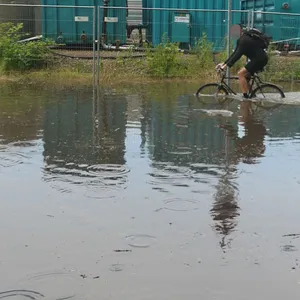 Radfahrer fährt durch tiefe Pfütze