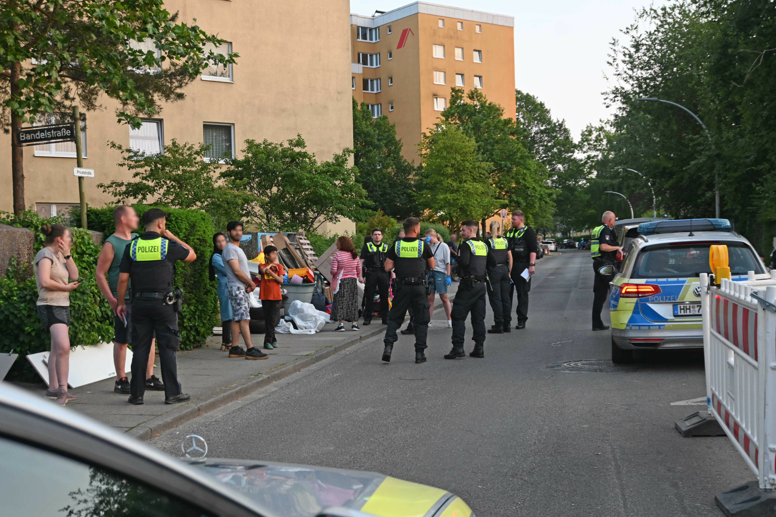 Polizei und mehrere Anwohner stehen am Gottschalkring vor Sperrmüllhaufen
