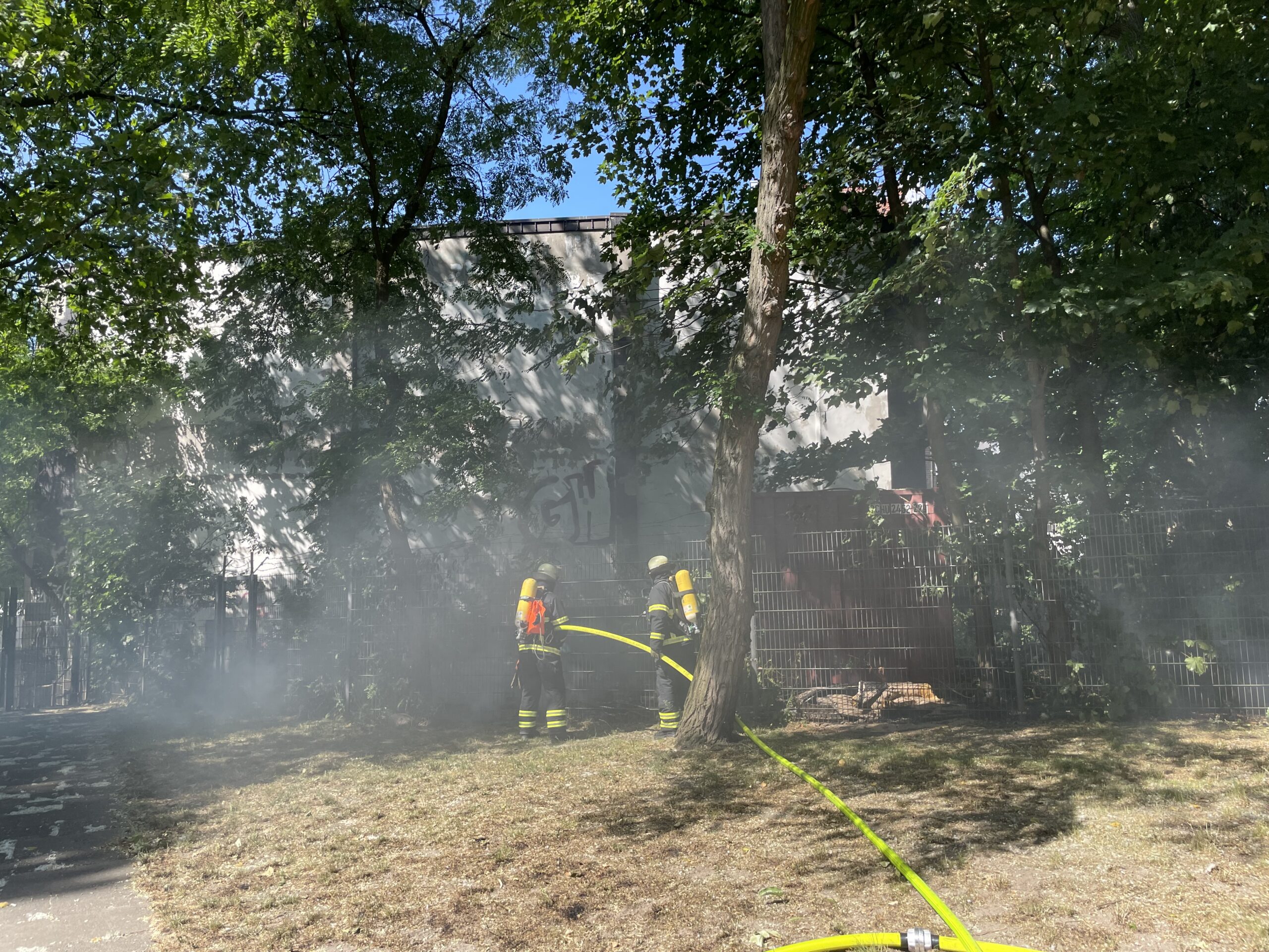 Feuerwehrleute löschen einen kleinen Brand auf einer Wiese.