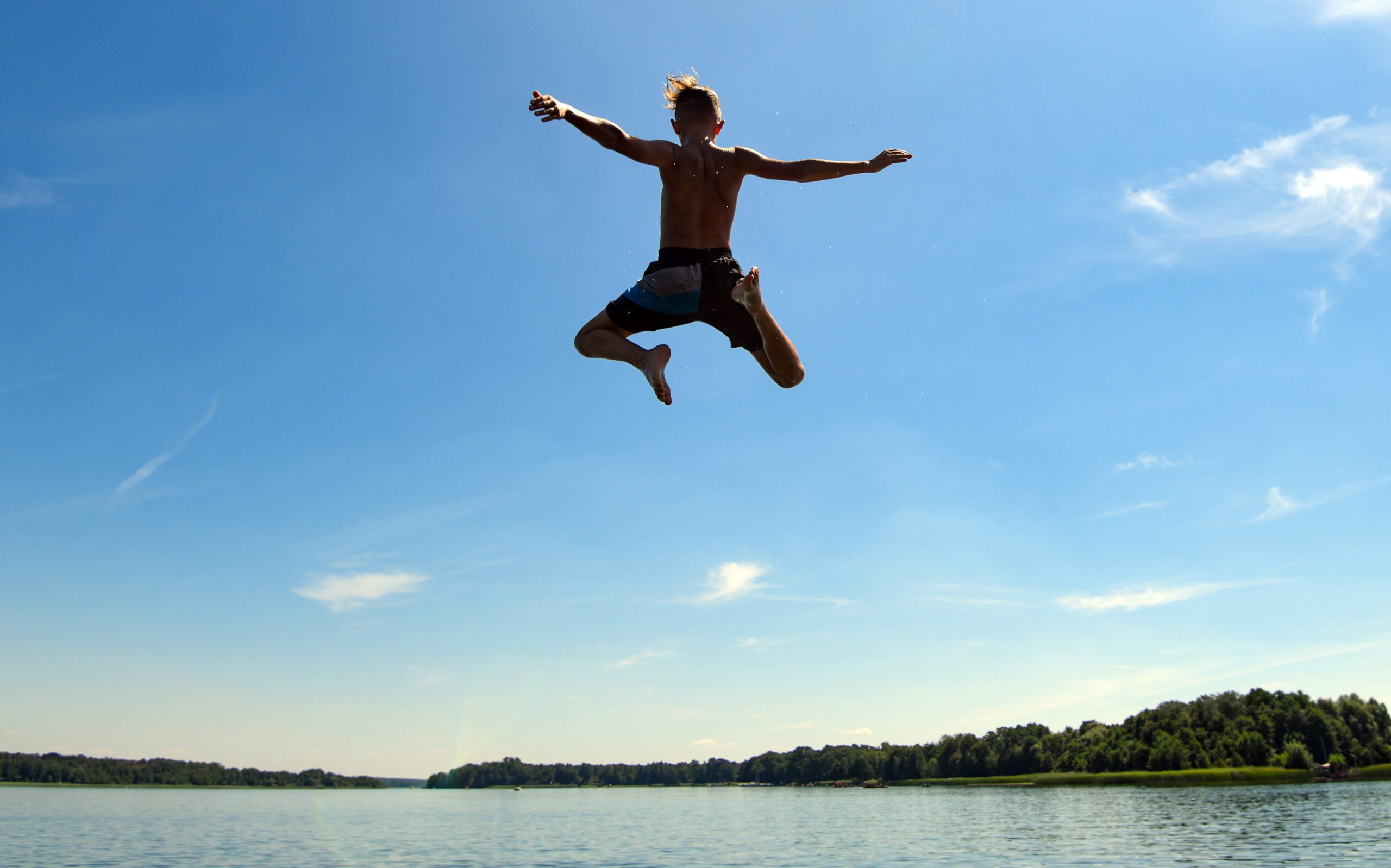 Junge springt ins Wasser eines Sees
