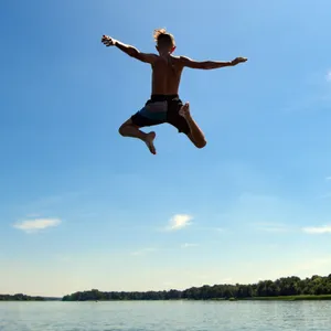 Junge springt ins Wasser eines Sees