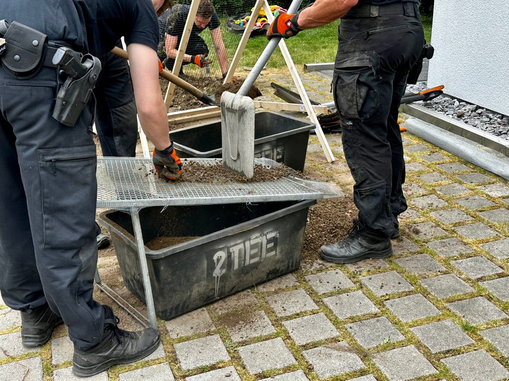 Polizeibeamte sieben die Erde auf der Suche nach Knochenteilen.