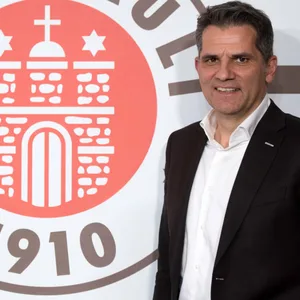 St. Paulis Vizepräsident Carsten Höltkemeyer posiert vor dem St. Pauli-Logo.