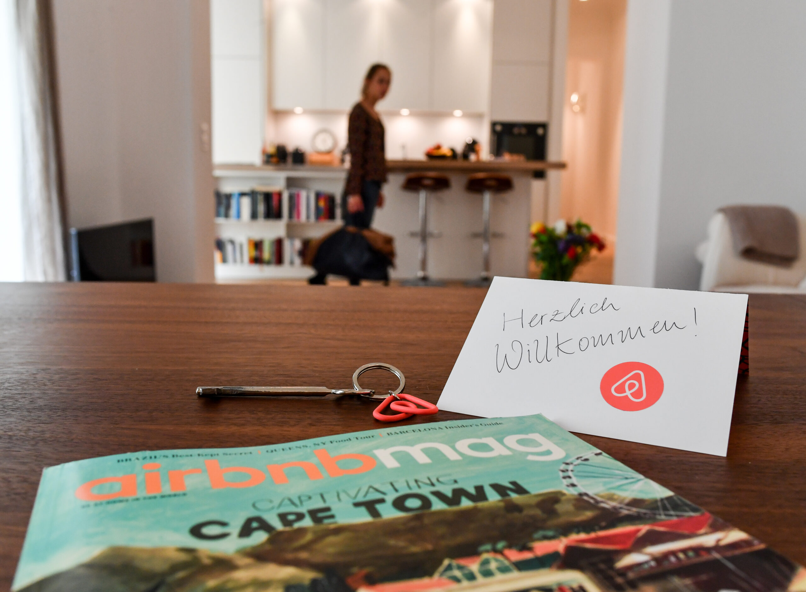 Ein Schlüssel mit einem Airbnb-Anhäger, ein Airbnbmag-Magazin und eine Herzlich-Willkommen-Karte liegen in der Wohnung eines Airbnb-Gastgebers