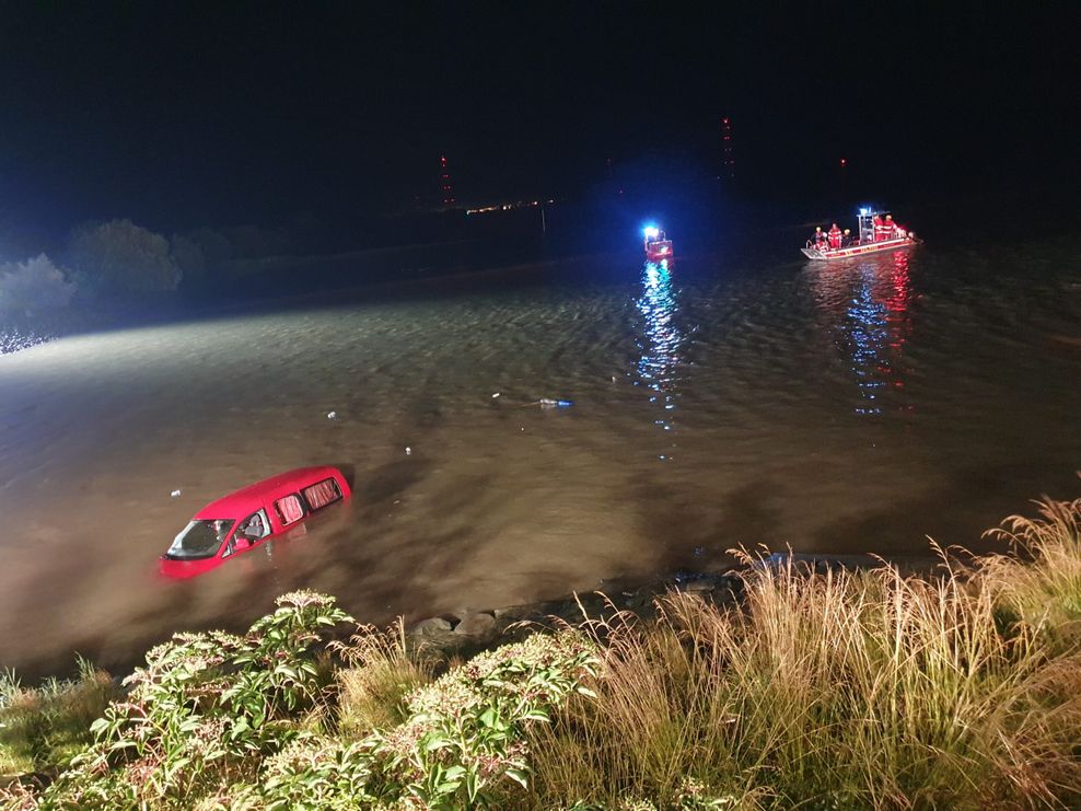 Ein roter PKW in der Elbe mit Rettungsboten der DLRG im Hintergrund