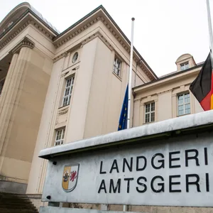 Schild mit Landgericht und Amtsgericht bedruck. Im Hintergrund ist das Gerichtsgebäude Schwerin zu sehen