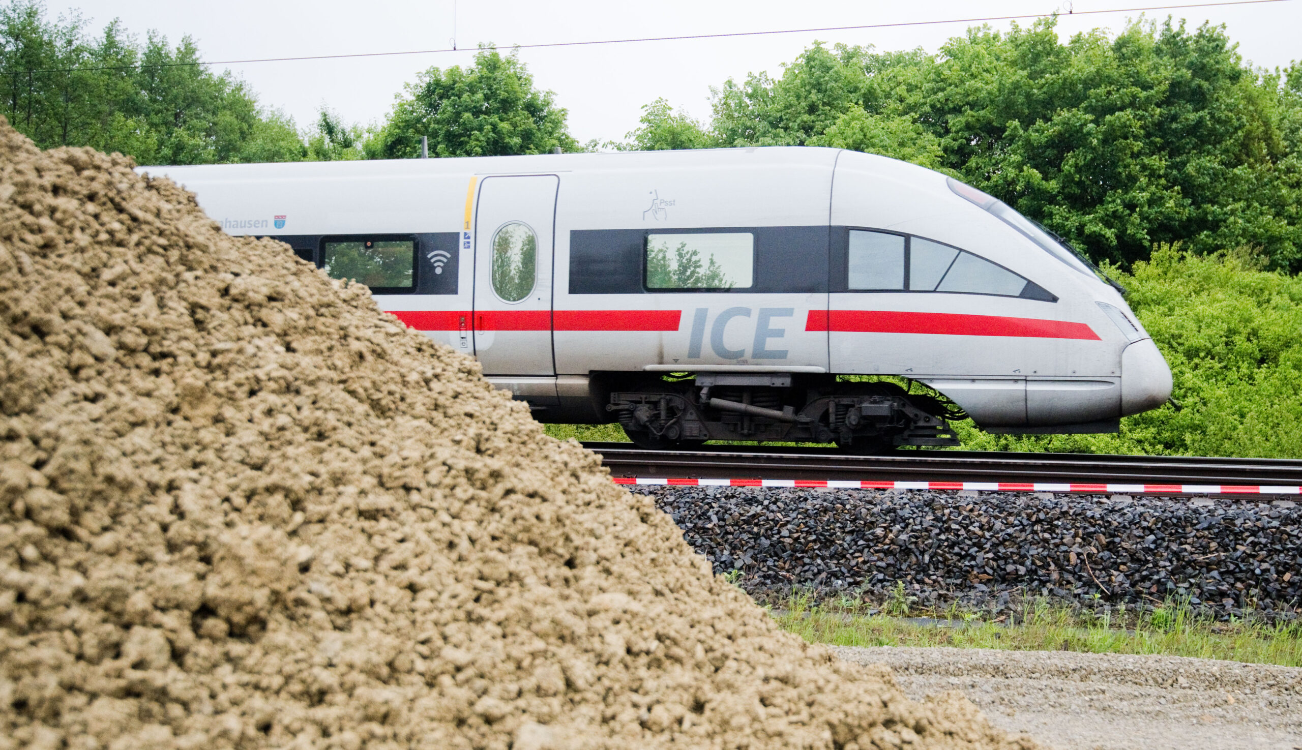 Deutsche Bahn ICE im Hintergrund, vorne links ein Erdhaufen.