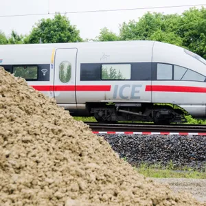 Deutsche Bahn ICE im Hintergrund, vorne links ein Erdhaufen.