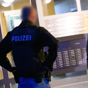 Ermittler stehen vor der Durchsuchung an einem Mehrfamilien-Hochhaus.