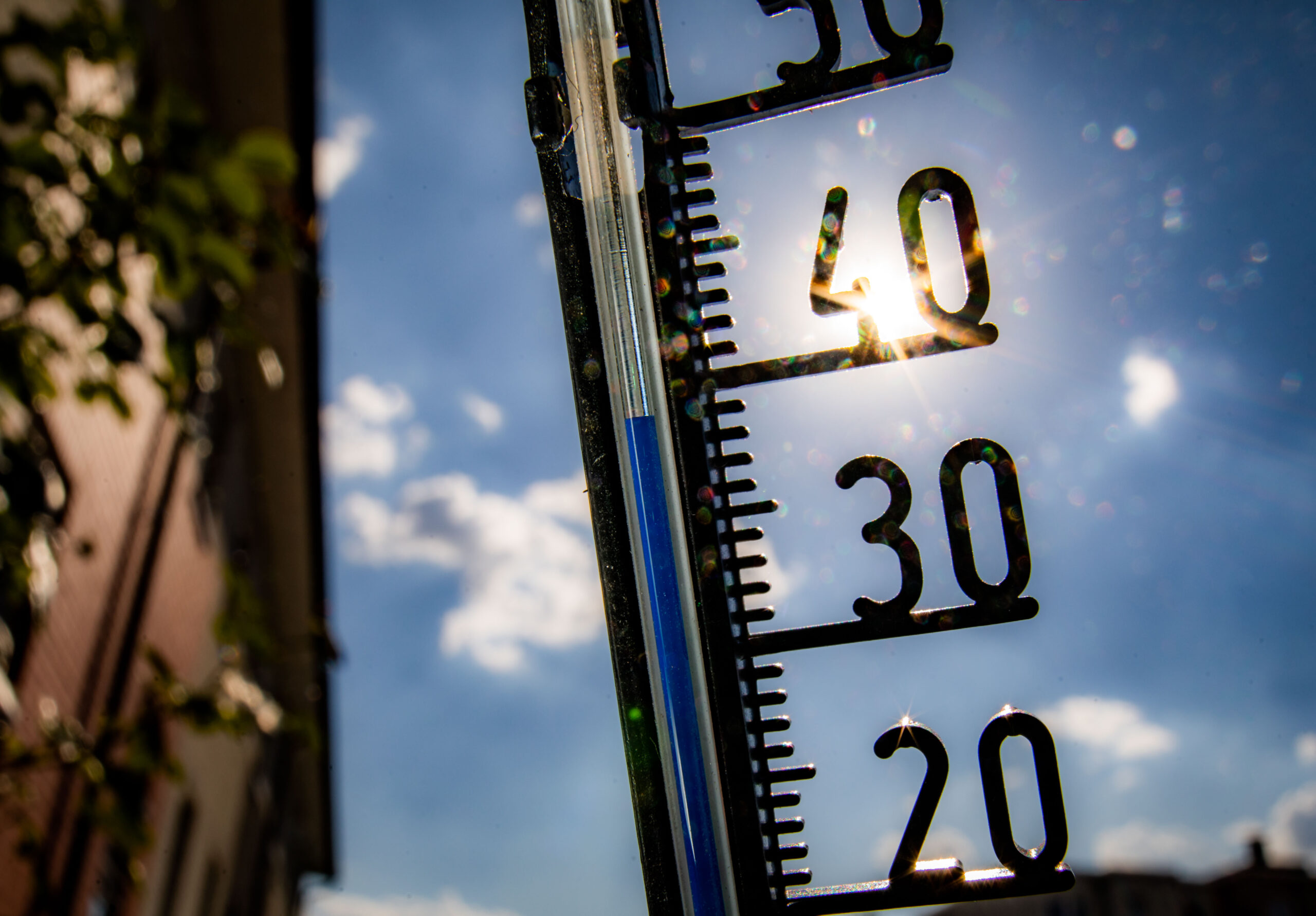 Ein Thermometer, das fast 40 Grad anzeigt. Im Hintergrund ist blauer Himmel, kaum Wolken und die Sonne zu sehen.