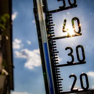 Ein Thermometer, das fast 40 Grad anzeigt. Im Hintergrund ist blauer Himmel, kaum Wolken und die Sonne zu sehen.
