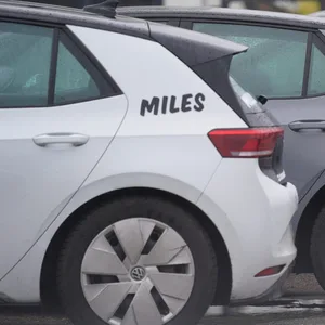 Elektrofahrzeuge des Carsharing-Dienstes Miles stehen an einem Straßenrand.