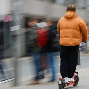 Ein Mann fährt auf einem E-Scooter durch die Stadt. (Symbolbild)